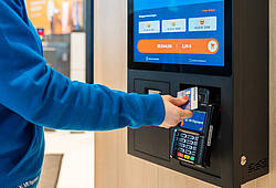 Ein Mann hält eine Karte an das Terminal eines Bezahlautomaten (Symbolbild).