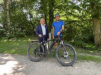 Zwei Männer freuen sich über ein E-Bike.