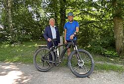 Zwei Männer freuen sich über ein E-Bike.