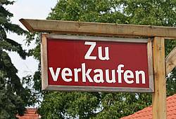 Ein Schild "Zu verkaufen" weist auf eine Immobilie zum Verkauf hin.