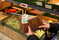Eine Frau öffnet im Supermarkt ihren Geldbeutel (Symbolbild für die hohe Inflation).
