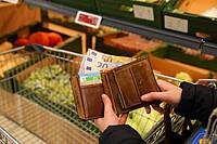 Eine Frau öffnet im Supermarkt ihren Geldbeutel (Symbolbild für die hohe Inflation).