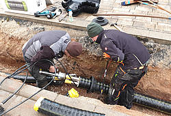 Zwei Handwerker arbeiten in Dornhausen an einer Rohrverbindung für ein Wärmenetz.