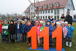 Gruppenfoto mit Schülern: Die Raiffeisenbank Pfaffenhausen pflanzt zum 111. Jubiläum einen Baum.