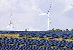 Windräder drehen sich am Horizont, im Vordergrund eine Photovoltaik-Anlage.