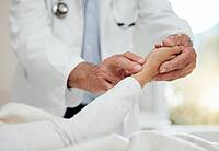 Ein Arzt fühlt bei einer Patientin den Puls.