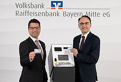 Andreas Streb (li.) und Richard L. Riedmaier von der Volksbank Raiffeisenbank Bayern Mitte präsentieren die VR-BitcoinGoCard.