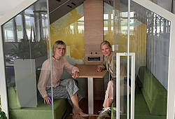 Zwei Frauen sitzen in einer Schaukel in einem Büro.