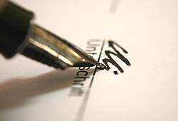 Eine Person unterschreibt mit Füller auf einem Dokument. Zu sehen ist nur die Spitze des Füllfederhalters (Symbolbild).