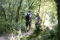 Ein älteres Paar läuft in Wanderkleidung durch den Wald.