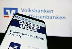 Ein Smartphone und ein Bildschirm, auf beiden ist der Schriftzug Volksbanken Raiffeisenbanken zu sehen.