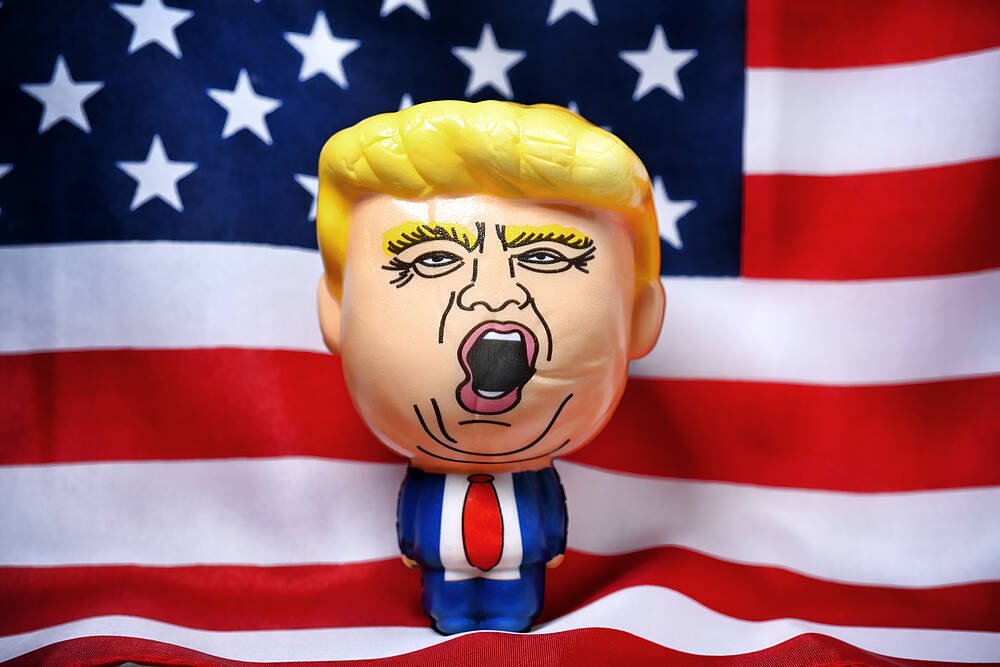 Eine Schaumgummi-Puppe mit dem Antlitz von US-Präsident Donald Trump steht vor einer US-Flagge (Symbolbild).