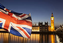 Eine britische Fahne weht im Wind, im Hintergrund das Parlament mit Big Ben.