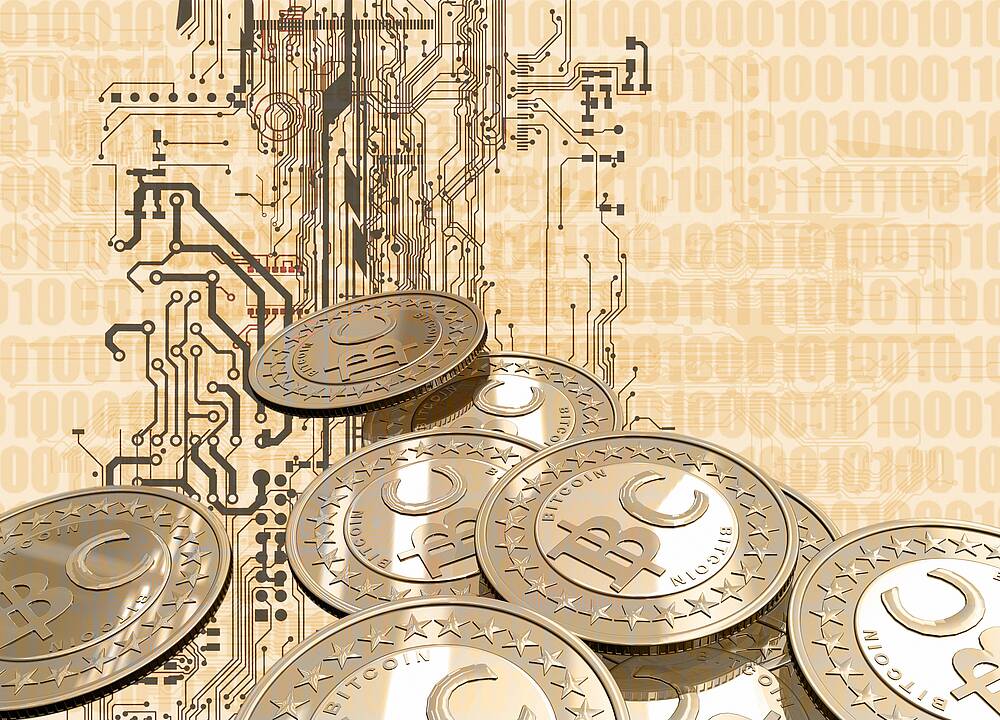 Eine Platine mit symbolischen Bitcoin-Münzen im Vordergrund (Symbolbild).