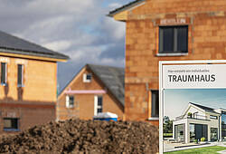Ein Schild mit der Aufschrift "Traumhaus" weist auf ein Neubaugebiet mit Wohnhäusern im Rohbau hin.