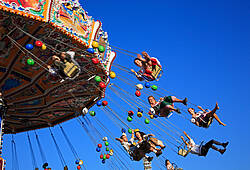 Menschen fliegen auf einem Kettenkarussel durch die Lüfte (Symbolbild).
