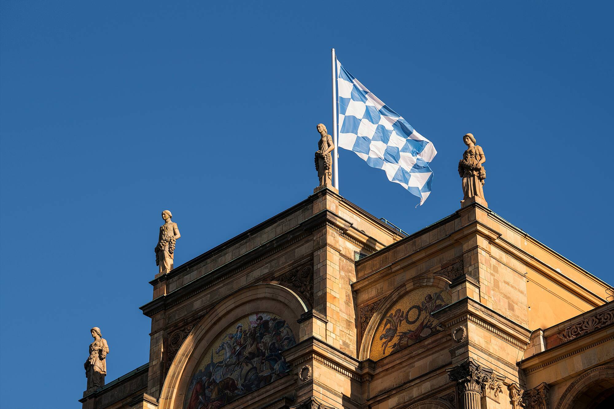 Blick auf das Maximilianeum in München, Sitz des Bayerischen Landtags. Auf dem Dach weht die bayerische Flagge mit weiß-blauen Rauten.