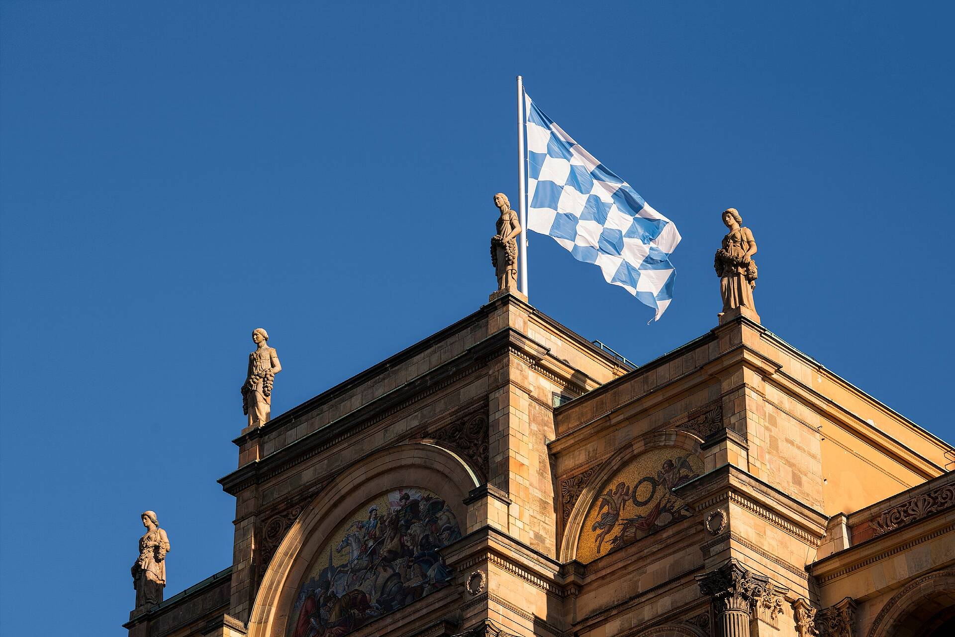 Blick auf das Maximilianeum in München, Sitz des Bayerischen Landtags. Auf dem Dach weht die bayerische Flagge mit weiß-blauen Rauten.