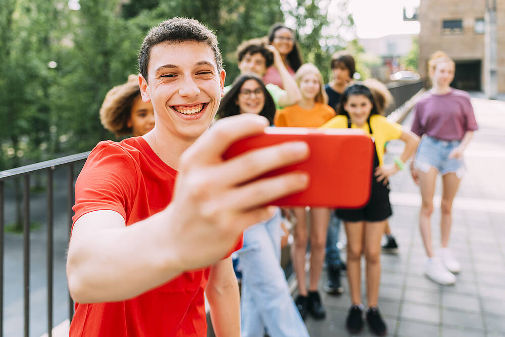Junger Mann macht ein Selfie von einer Gruppe 