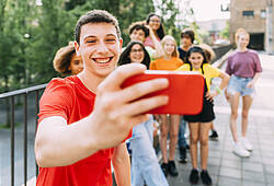 Ein Jugendlicher macht ein Selfie mit einer Gruppe junger Menschen.